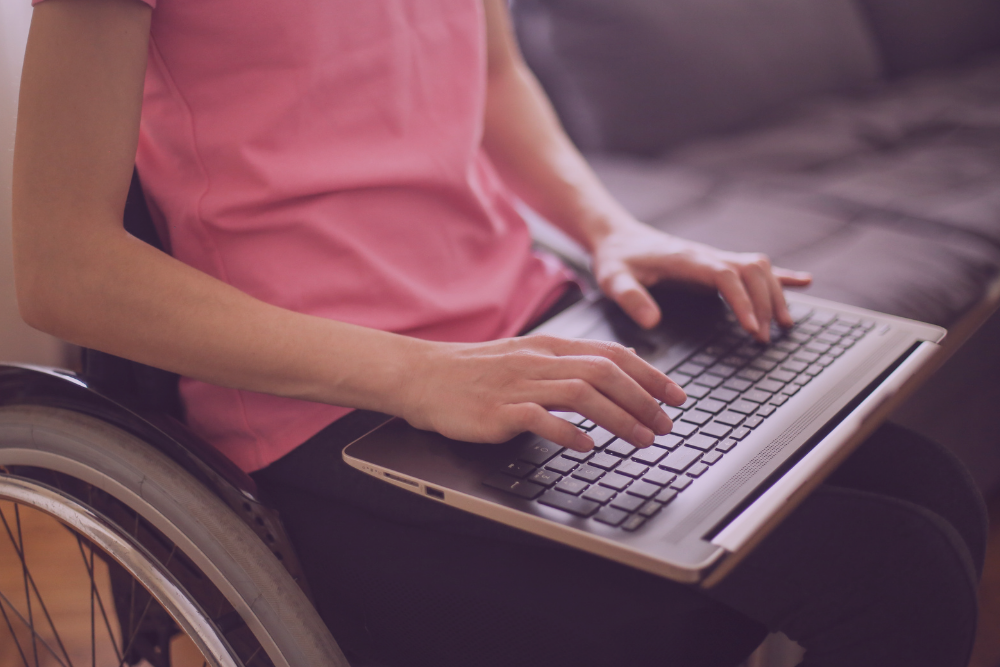 Mujer en silla de ruedas escribiendo en un ordenador portátil