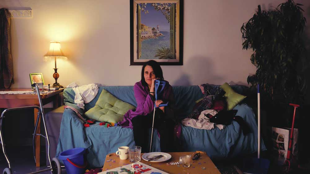 Mujer con discapacidad sentada en el sofá de su casa mirando a cámara