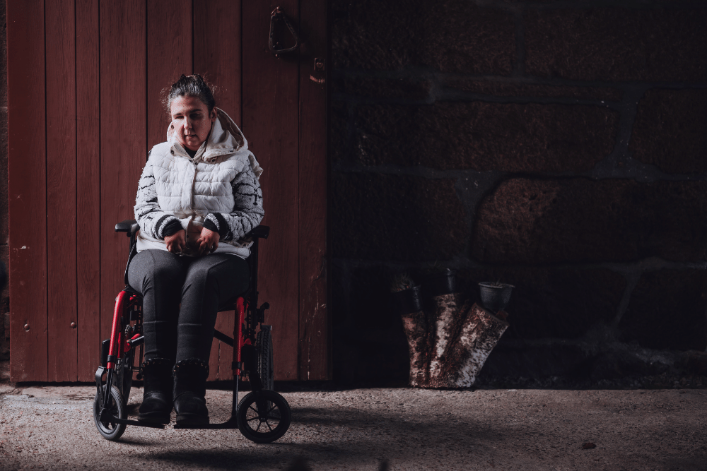 Mujer con discapacidad en silla de ruedas en una habitación sola y triste