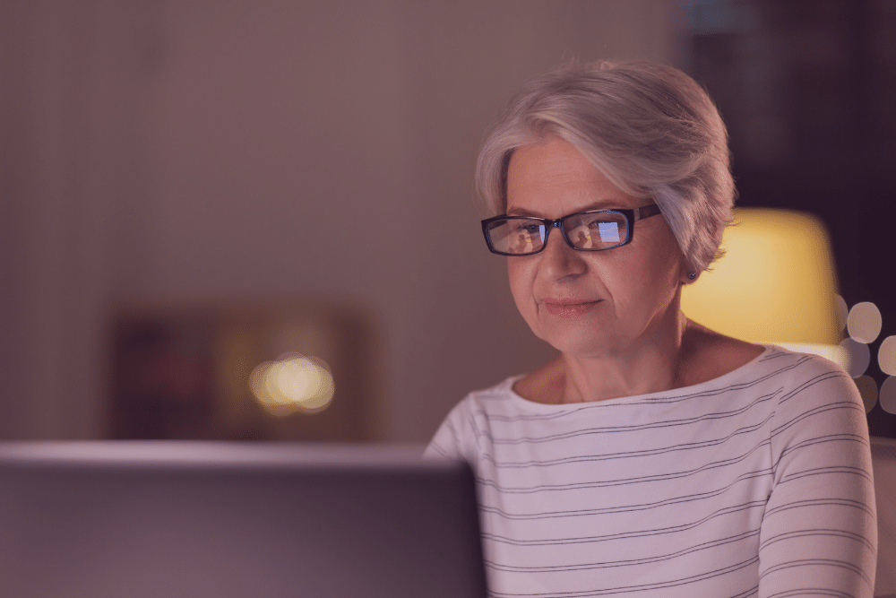 Mujer mayor con gafas usando un ordenador
