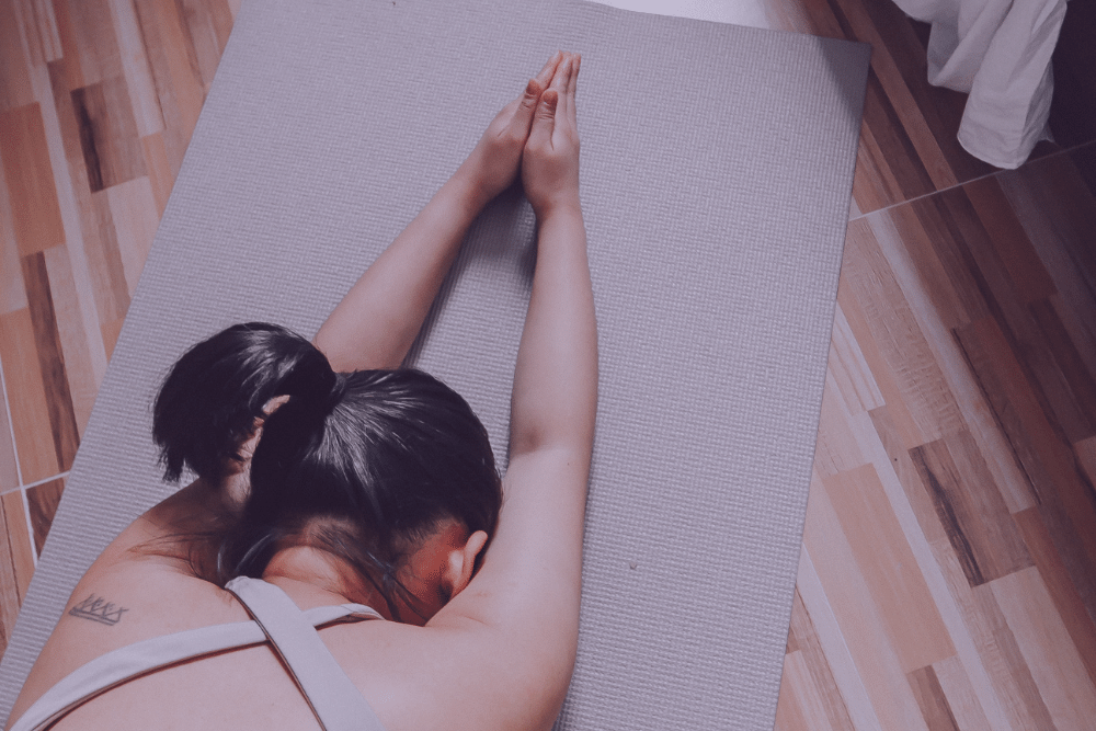 Mujer estirando los brazos en una esterilla de yoga para fortalecer su suelo pélvico