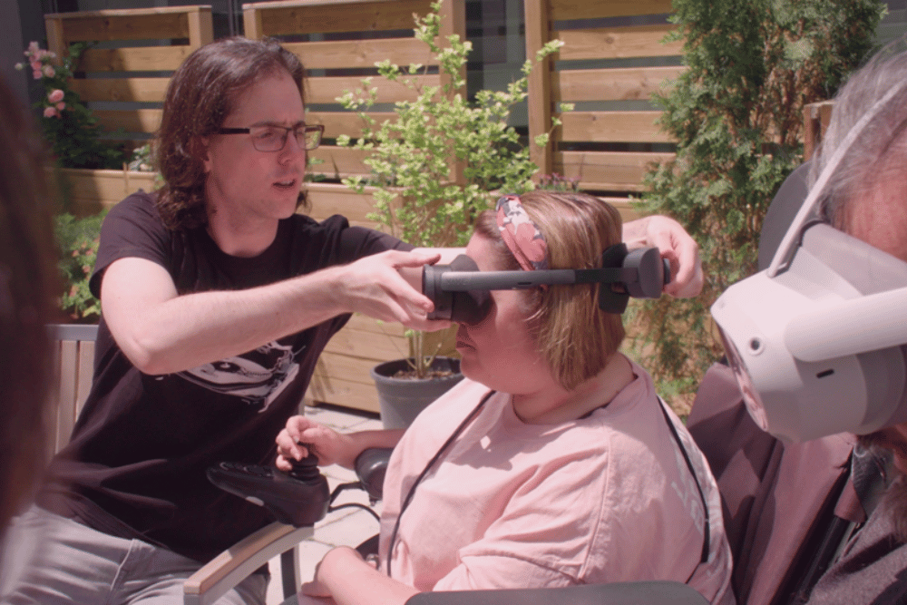 Hombre ayudando a colocarse una gafas de realidad virtual a una mujer con discapacidad